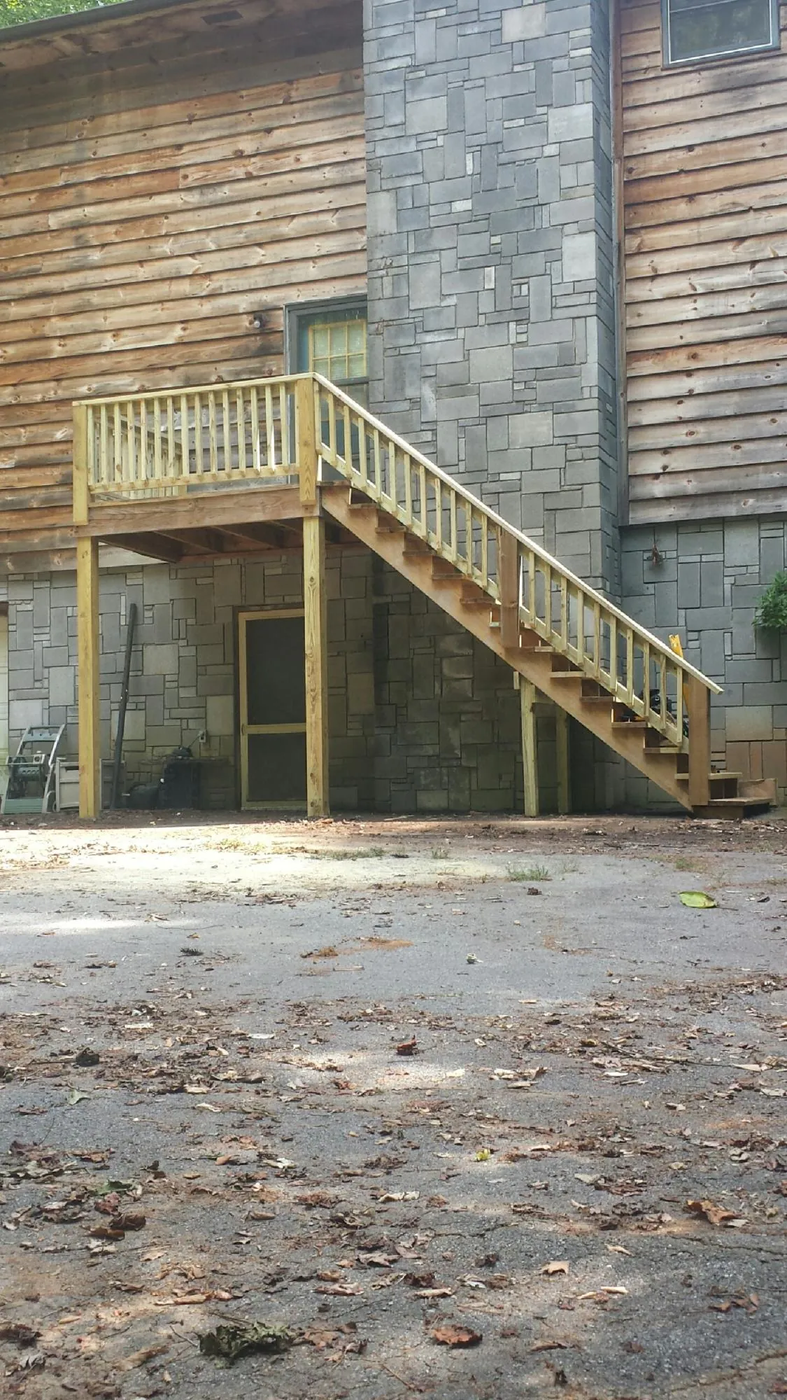 New pressure treated deck and stair landing on a log home in Bighorn