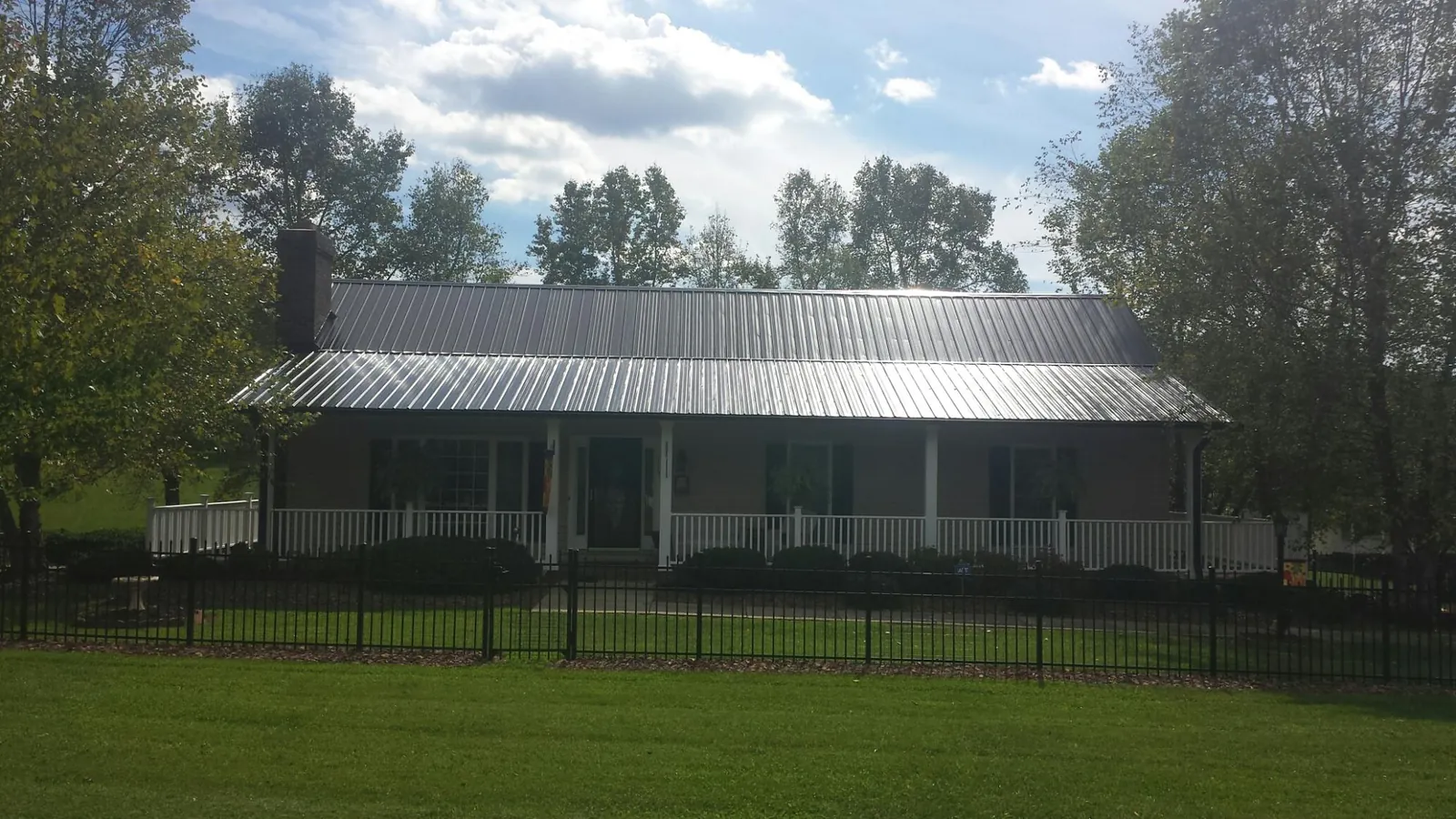 Gray metal roof on a brick ranch with a full width front porch — Gutter Guard Installation work by our crew in Bighorn