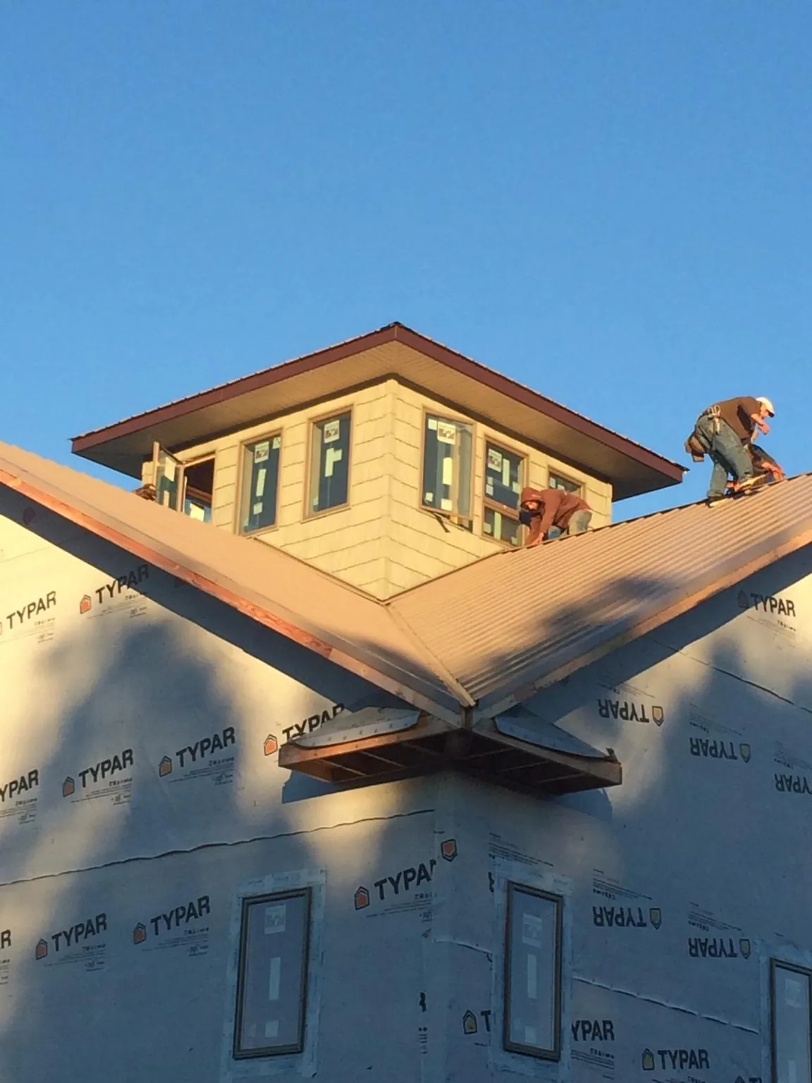 Roofers working around a rooftop cupola on a new metal roof at sunset — Roof Waterproofing in Bighorn by Roofing Brothers